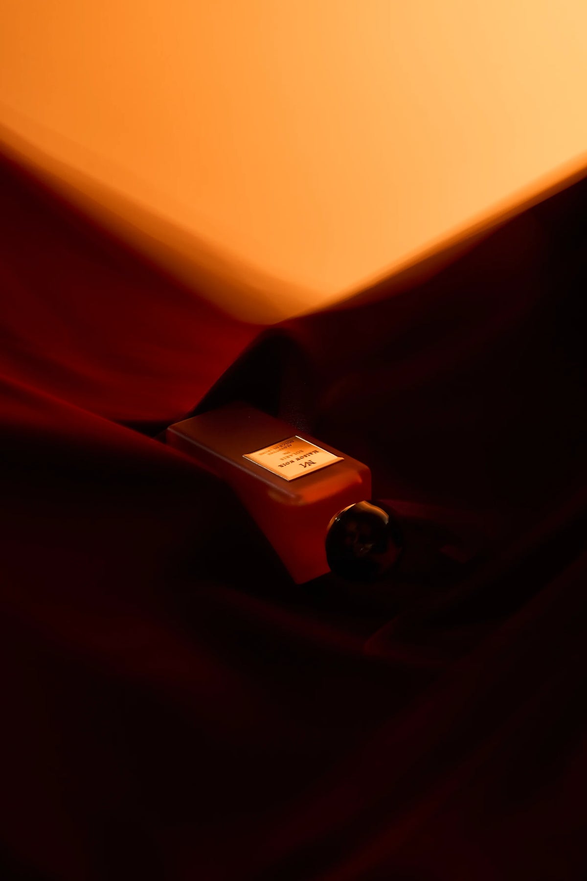 A flacon on a terracotta ground under hard directional light