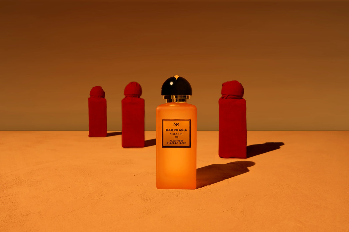 Three Maison Noir flacons against a warm amber ground