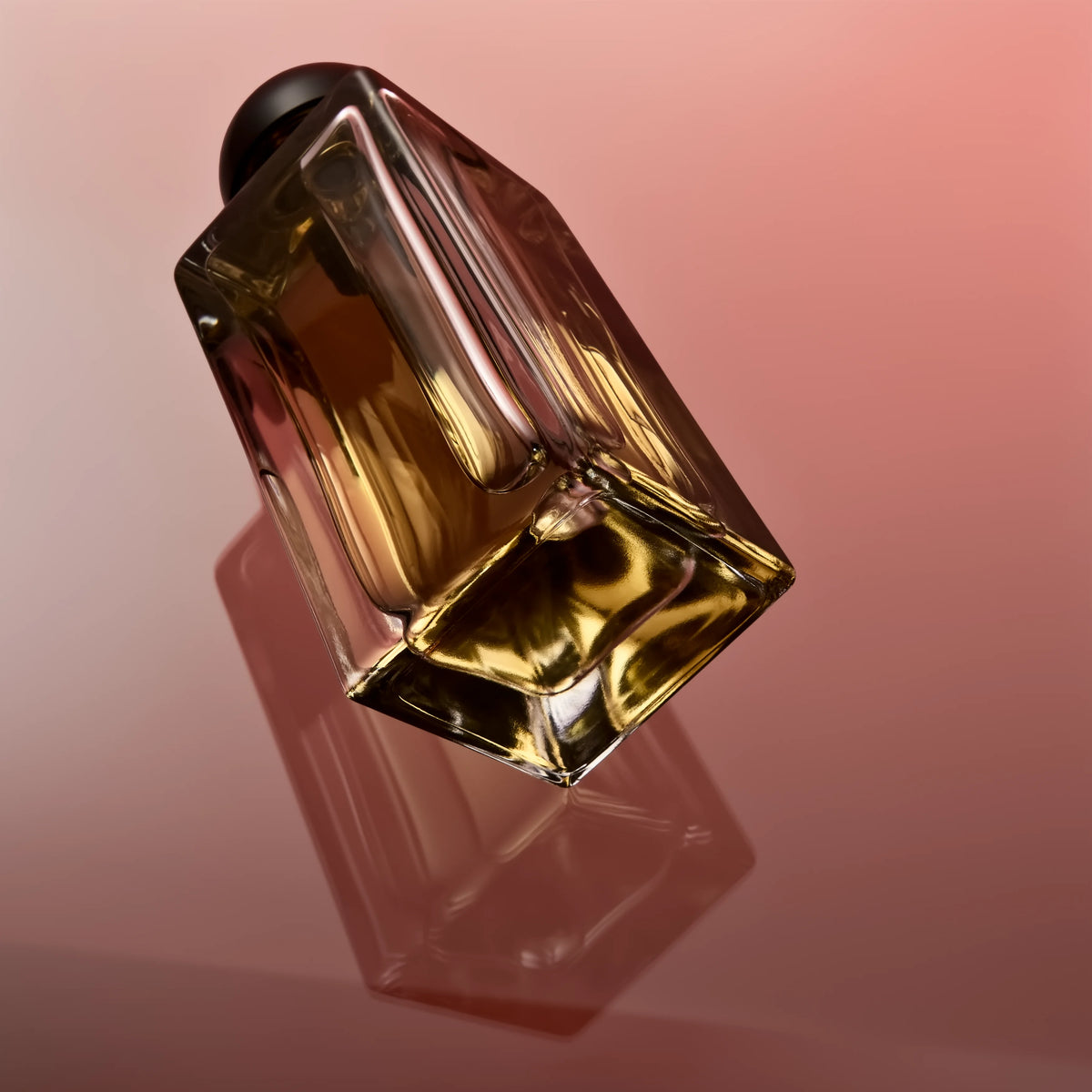 A tilted glass perfume bottle with a dark cap containing golden-yellow liquid against a pink background, casting a shadow on the surface